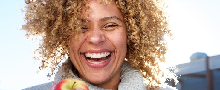 Lachende vrouw met appel in haar hand