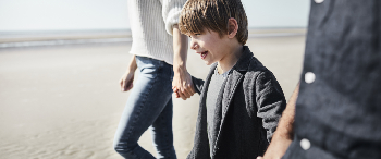 Kind loopt met ouders over strand
