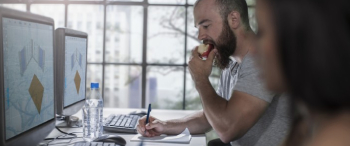 Man appel aan het eten terwijl hij aan het werk is naast een collega
