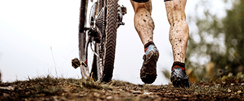 Fietser loopt naast fiets door de modder
