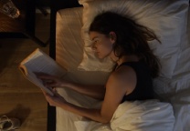Vrouw die in bed een boek aan het lezen is