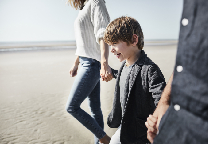 Kind loopt met ouders over strand