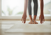 Dame op yogamat buigt voorover