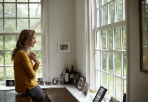Vrouw met kop thee voor het raam