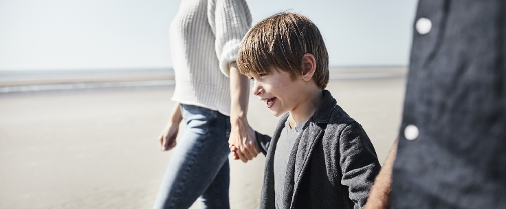 Kind loopt met ouders over strand