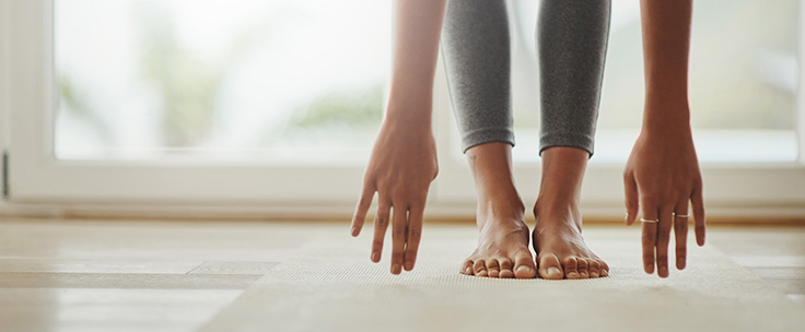 Dame op yogamat buigt voorover