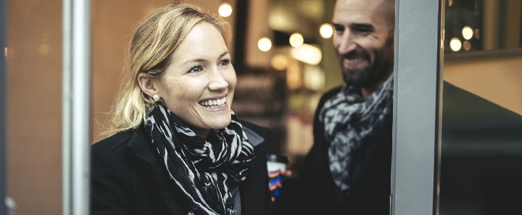 Man en vrouw lopen naar buiten met koffie