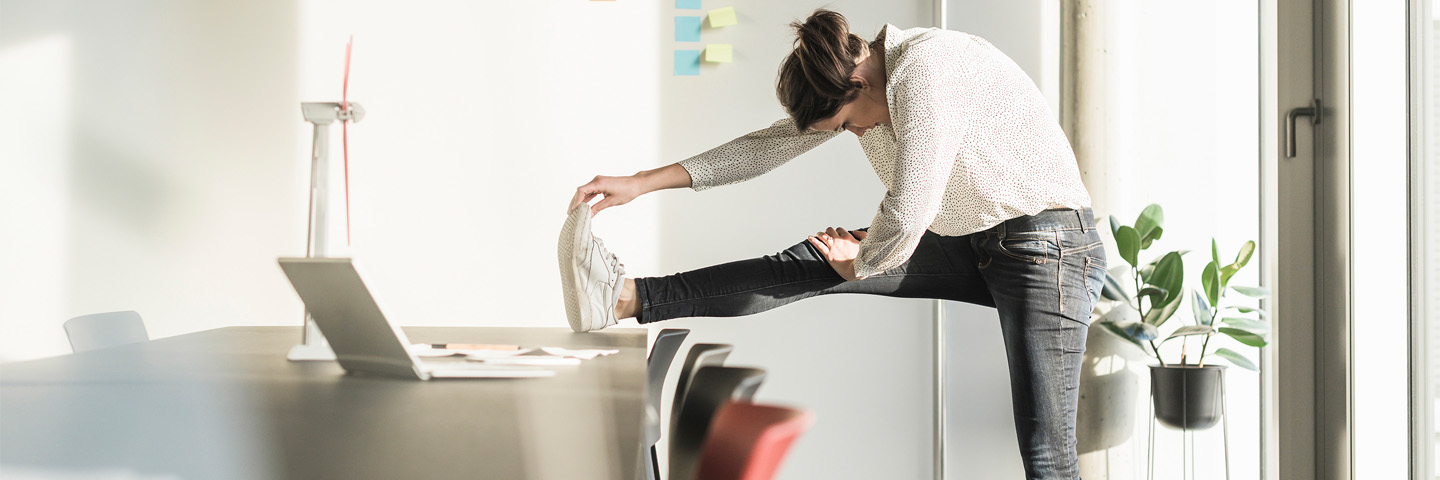 vrouw strekt been op bureau